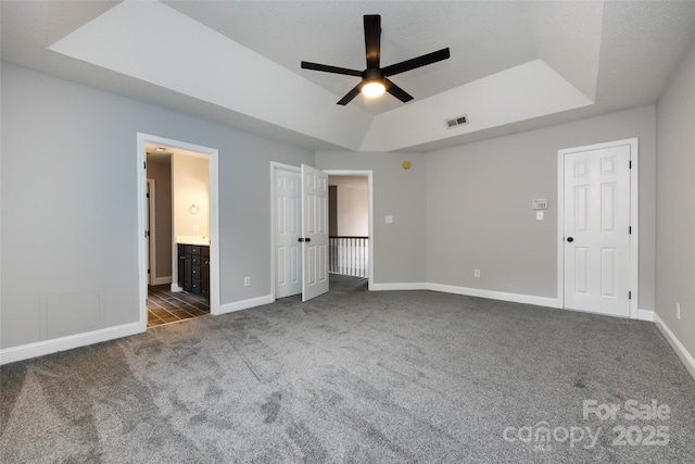 1309 Stonewyck Dr, Salisbury, NC 28146 - unfurnished bedroom with dark colored carpet, a raised ceiling, connected bathroom, and a ceiling fan