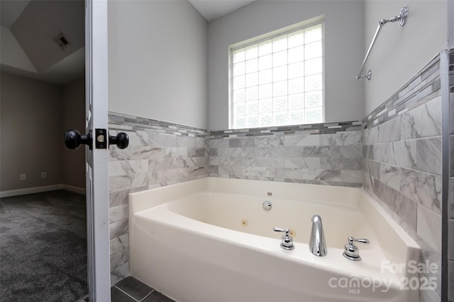 1309 Stonewyck Dr, Salisbury, NC 28146 - bathroom featuring a tub with jets, tile walls, and wainscoting