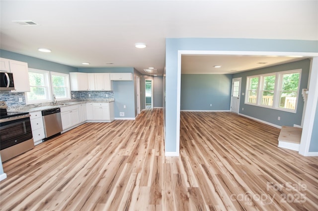 113 Oakleaf Dr, Landrum, SC 29356 - kitchen with appliances with stainless steel finishes, open floor plan, white cabinets, decorative backsplash, and light wood finished floors