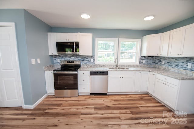 113 Oakleaf Dr, Landrum, SC 29356 - kitchen with stainless steel appliances, light wood finished floors, tasteful backsplash, white cabinetry, and light stone counters