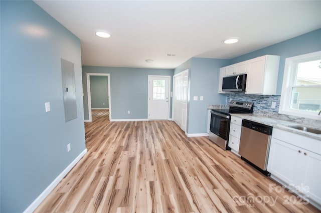 113 Oakleaf Dr, Landrum, SC 29356 - kitchen featuring stainless steel appliances, white cabinets, tasteful backsplash, light wood-style floors, and light stone counters