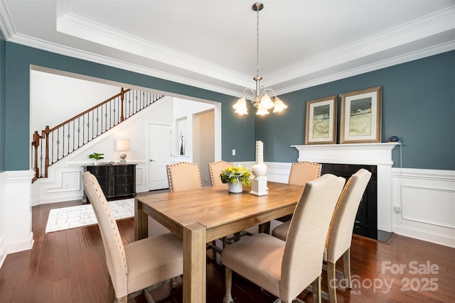 3021 Henshaw Rd, Waxhaw, NC 28173 - dining space featuring dark wood finished floors, crown molding, stairway, a wainscoted wall, and a tray ceiling