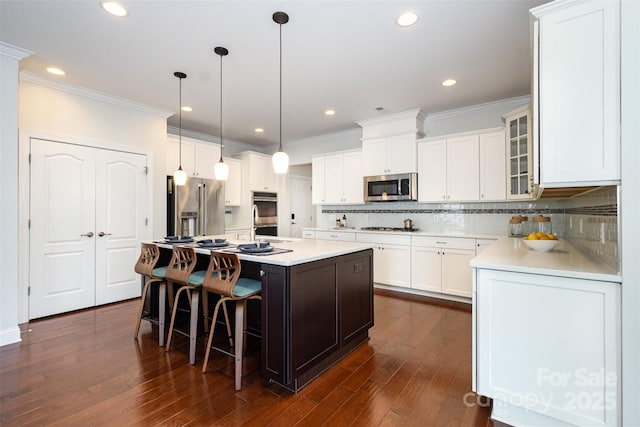 3021 Henshaw Rd, Waxhaw, NC 28173 - kitchen featuring crown molding, appliances with stainless steel finishes, a kitchen island with sink, a kitchen bar, and glass insert cabinets