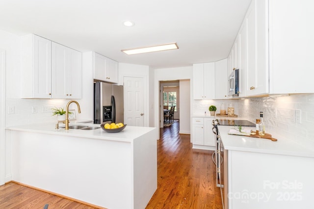 444 Cottonfield Cir, Waxhaw, NC 28173 - kitchen featuring a peninsula, stainless steel appliances, light wood finished floors, tasteful backsplash, and recessed lighting