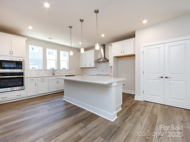 7004 Impulse Ct, Charlotte, NC 28205 - kitchen with stainless steel oven, light countertops, white cabinets, backsplash, and wall chimney exhaust hood