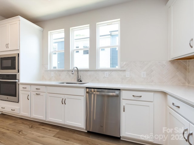 7004 Impulse Ct, Charlotte, NC 28205 - kitchen featuring appliances with stainless steel finishes, decorative backsplash, white cabinetry, light countertops, and light wood finished floors