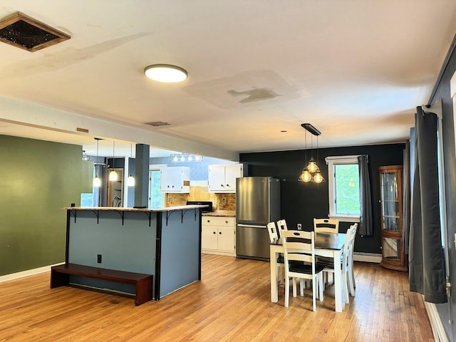 491 W Main St, Waldoboro, ME 04572 - kitchen featuring freestanding refrigerator, white cabinets, a baseboard radiator, light wood-style flooring, and a kitchen bar