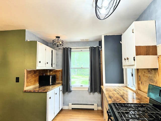 491 W Main St, Waldoboro, ME 04572 - kitchen featuring black range with gas stovetop, baseboard heating, stainless steel microwave, light wood-type flooring, and white cabinets