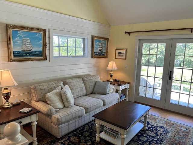 living room featuring wooden walls, vaulted ceiling, and hardwood / wood-style floors