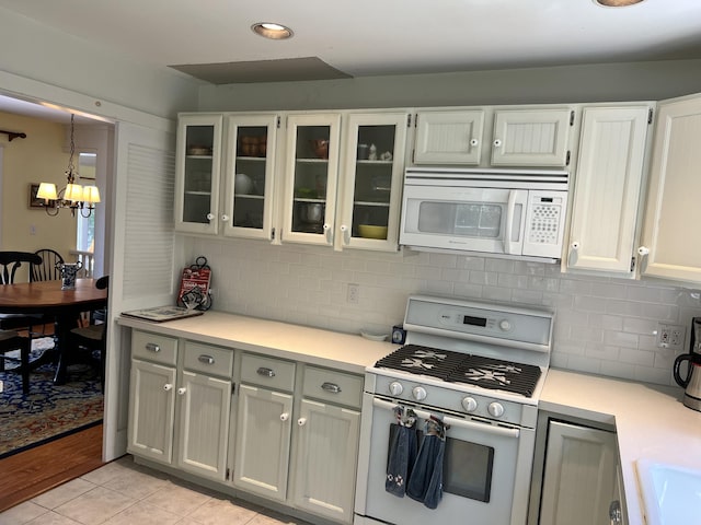 kitchen with pendant lighting, light tile patterned floors, white appliances, and white cabinets