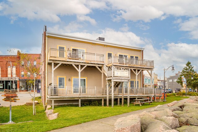 rear view of property with a yard and a balcony