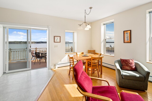 dining room with a notable chandelier, a water view, a wealth of natural light, and light wood-type flooring