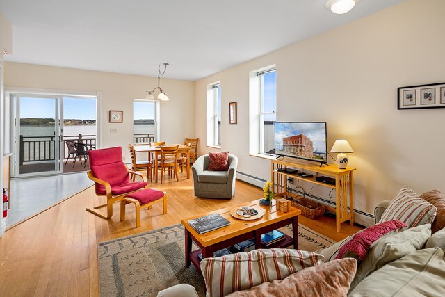 living room featuring a water view, light hardwood / wood-style floors, and a baseboard heating unit