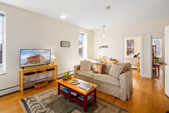 living room with baseboard heating and light wood-type flooring