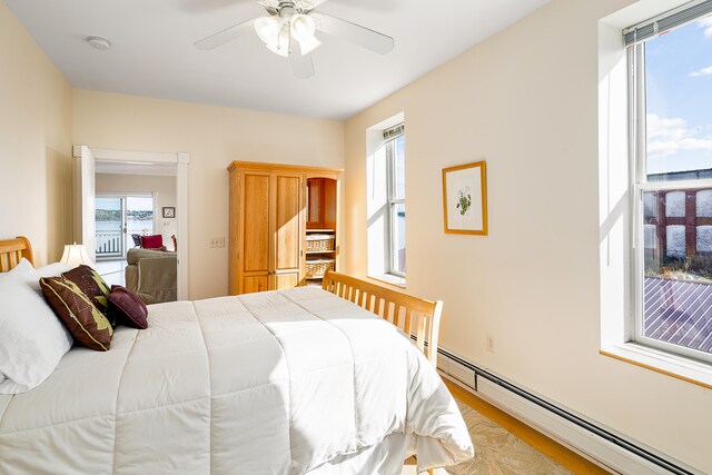 bedroom featuring ceiling fan, baseboard heating, and light wood-type flooring