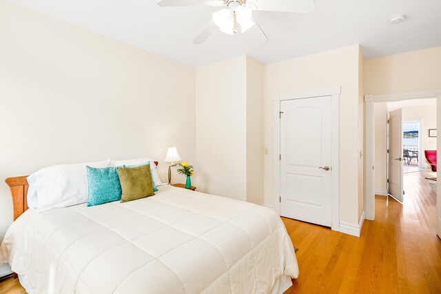 bedroom featuring light hardwood / wood-style floors, ceiling fan, and a baseboard heating unit