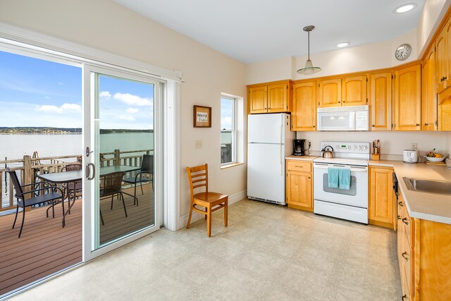 kitchen featuring hanging light fixtures, white appliances, light tile flooring, and a water view