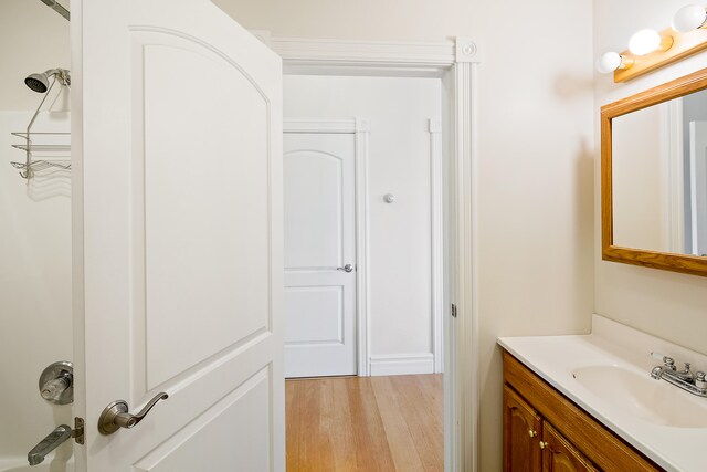 bathroom with vanity with extensive cabinet space, hardwood / wood-style flooring, and tub / shower combination