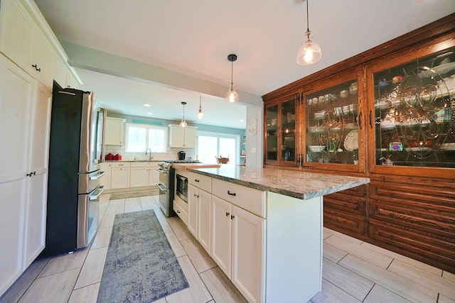 428 Main St, Orono, ME 04473 - kitchen with appliances with stainless steel finishes, a sink, a center island, light stone counters, and hanging light fixtures