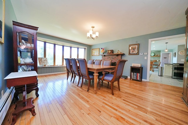 428 Main St, Orono, ME 04473 - dining area featuring a chandelier, a baseboard radiator, light wood-style flooring, and baseboards
