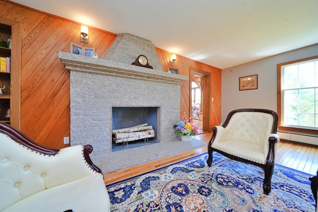428 Main St, Orono, ME 04473 - living area featuring wooden walls, wood finished floors, a fireplace, and a baseboard heating unit