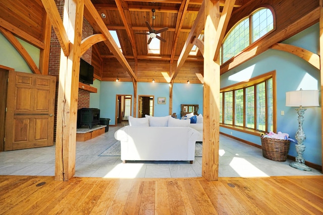 428 Main St, Orono, ME 04473 - living area with wooden ceiling with exposed beams, high vaulted ceiling, a ceiling fan, a wood stove, and hardwood / wood-style flooring