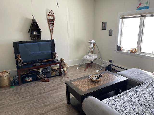 living room with baseboard heating, a healthy amount of sunlight, and hardwood / wood-style floors