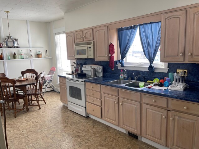 kitchen with light tile floors, hanging light fixtures, white appliances, and sink