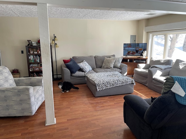 living room with a textured ceiling, baseboard heating, and hardwood / wood-style flooring