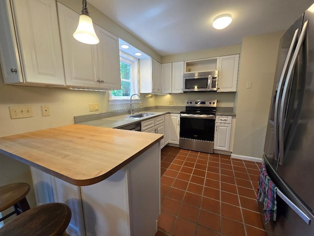 40 Willow Grove Rd, Brunswick, ME 04011 - kitchen featuring stainless steel appliances, a kitchen breakfast bar, white cabinets, a peninsula, and dark tile patterned flooring