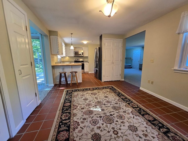40 Willow Grove Rd, Brunswick, ME 04011 - kitchen with stainless steel appliances, white cabinetry, a peninsula, a breakfast bar, and dark tile patterned flooring