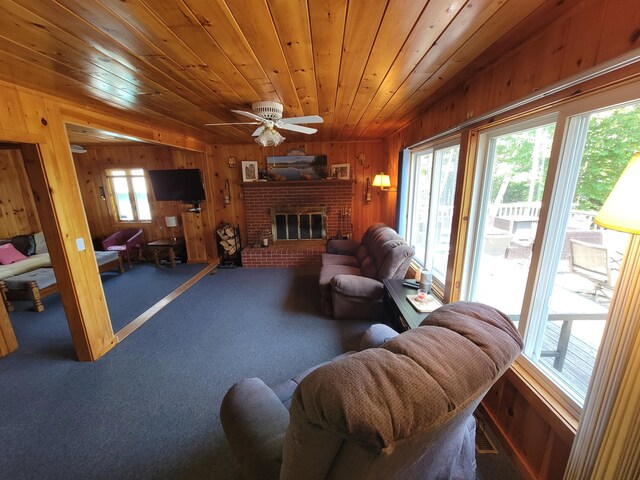 living room featuring ceiling fan, a healthy amount of sunlight, a fireplace, and wood ceiling