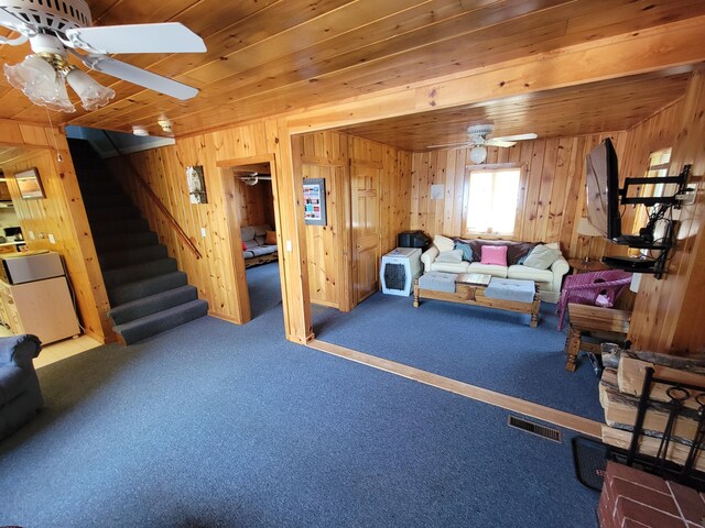 living room with wood ceiling, dark carpet, ceiling fan, and wood walls