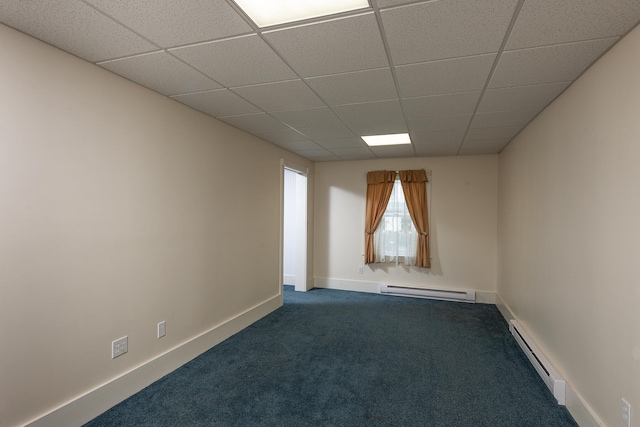 empty room with a baseboard radiator, a paneled ceiling, and dark carpet