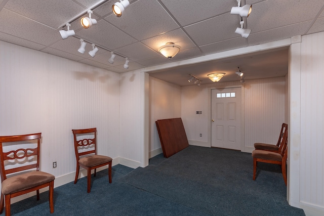 living area with a paneled ceiling, dark carpet, and rail lighting