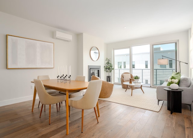 dining area with wood-type flooring and a wall mounted AC