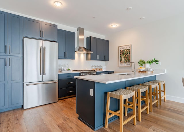kitchen with a breakfast bar, wall chimney range hood, a peninsula, and high end refrigerator