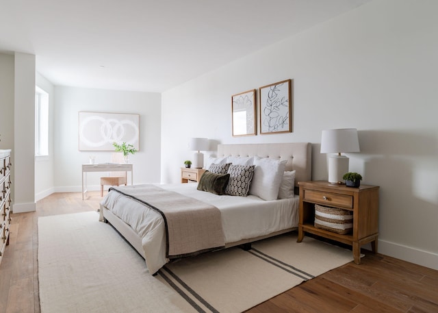 bedroom featuring light wood finished floors and baseboards