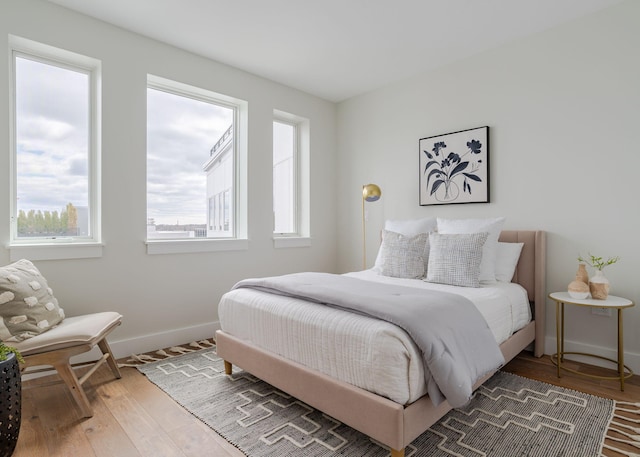 bedroom featuring baseboards, wood finished floors, and multiple windows