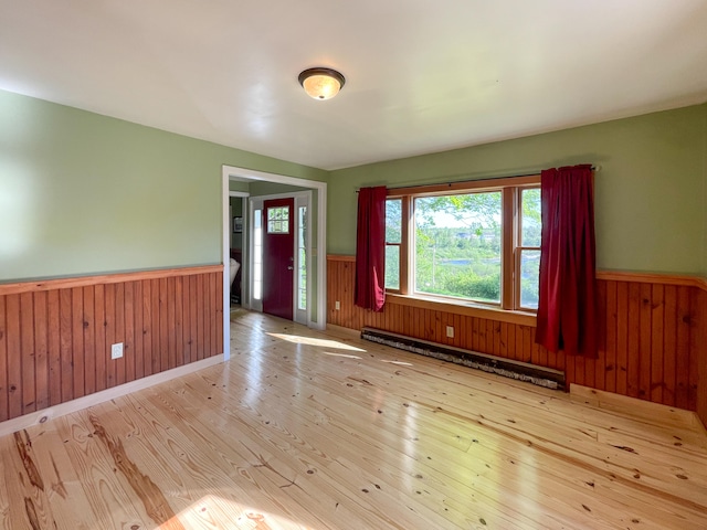 spare room featuring baseboard heating and light wood-type flooring