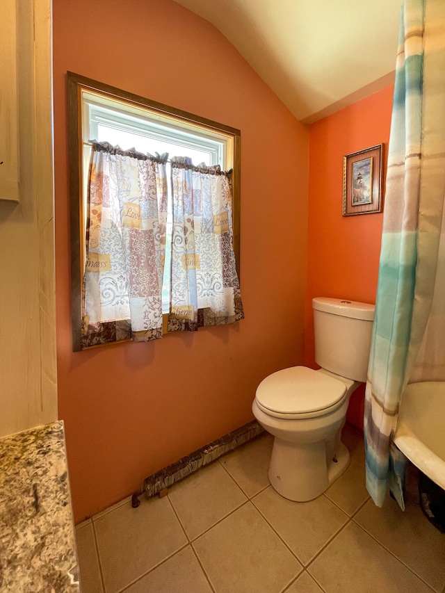 bathroom with lofted ceiling, tile floors, and toilet