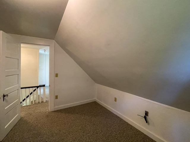 bonus room with dark carpet and lofted ceiling