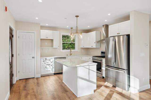 kitchen featuring a center island, white cabinets, stainless steel appliances, and wall chimney exhaust hood