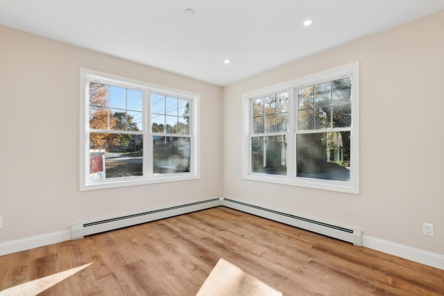 spare room with baseboards, a baseboard radiator, recessed lighting, and wood finished floors