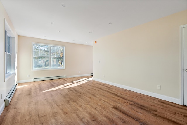 unfurnished room with baseboards, baseboard heating, and light wood finished floors