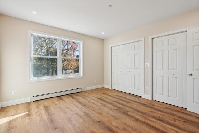 unfurnished bedroom with multiple closets, wood finished floors, baseboards, recessed lighting, and a baseboard radiator