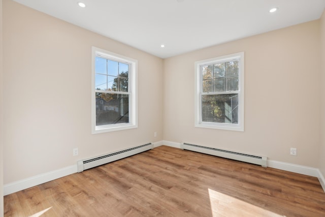empty room with light wood-style floors, a baseboard radiator, baseboards, and recessed lighting
