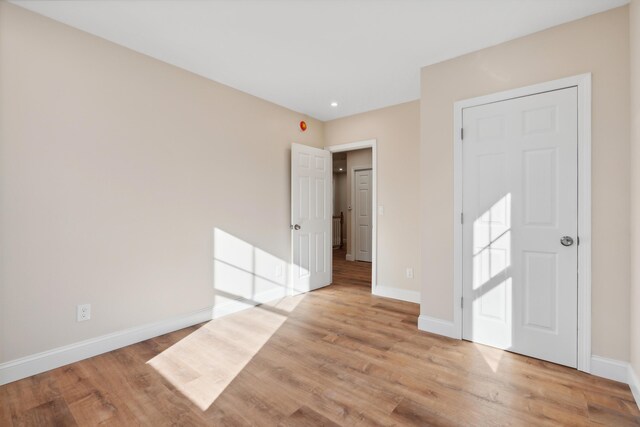 unfurnished bedroom featuring baseboards, recessed lighting, and light wood finished floors