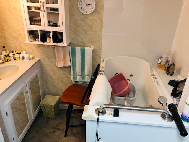 bathroom featuring tile flooring, vanity, and a washtub