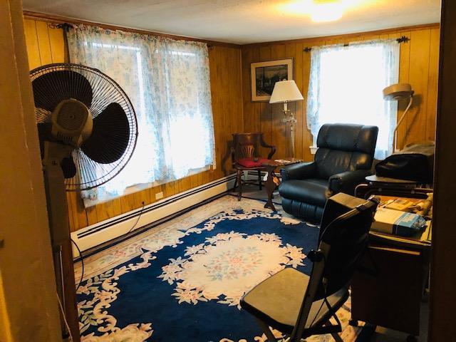 home office with wood walls and a baseboard heating unit